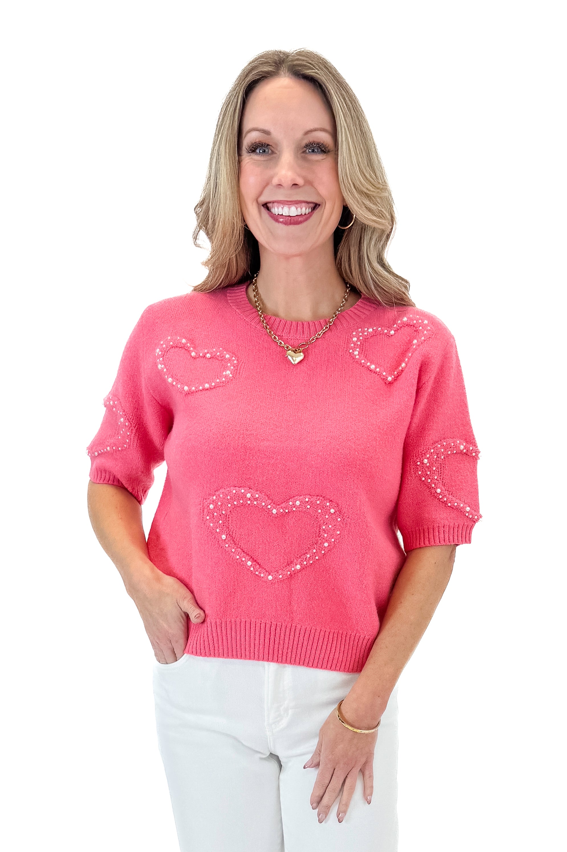 Front view of woman wearing Pink With Pearl Heart Detail Sweater with jeans against white studio background. 