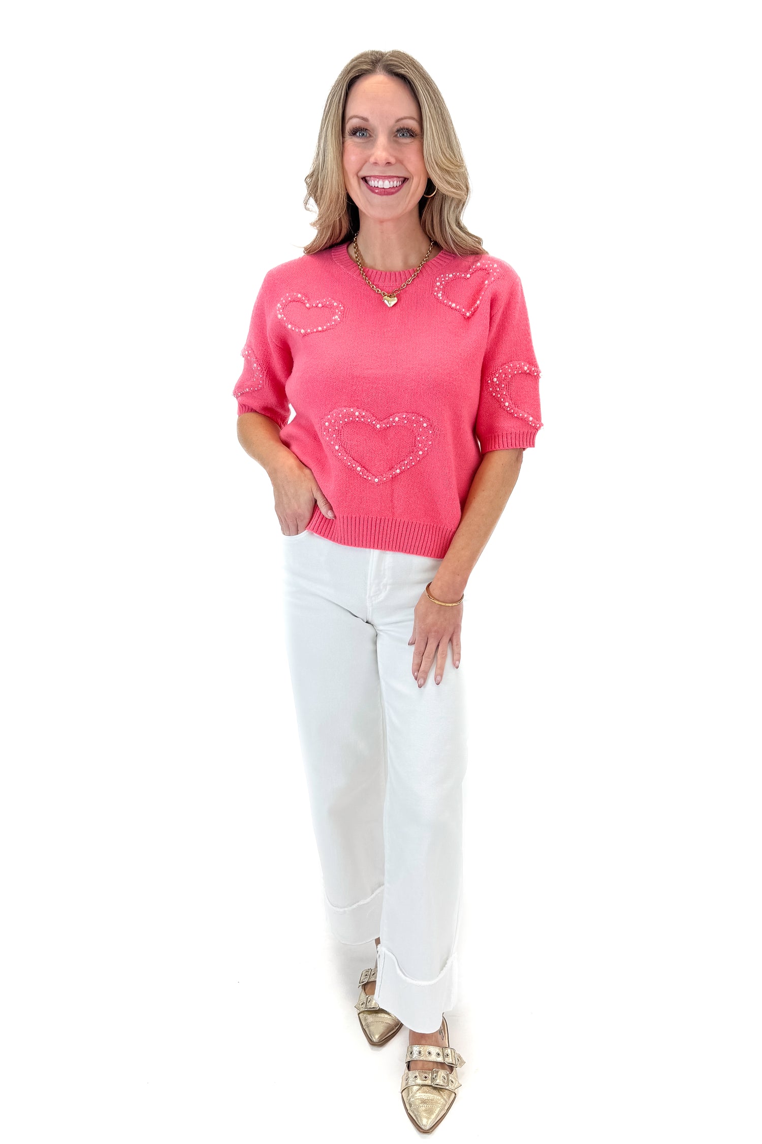 Front view of woman wearing Pink With Pearl Heart Detail Sweater with jeans against white studio background. 