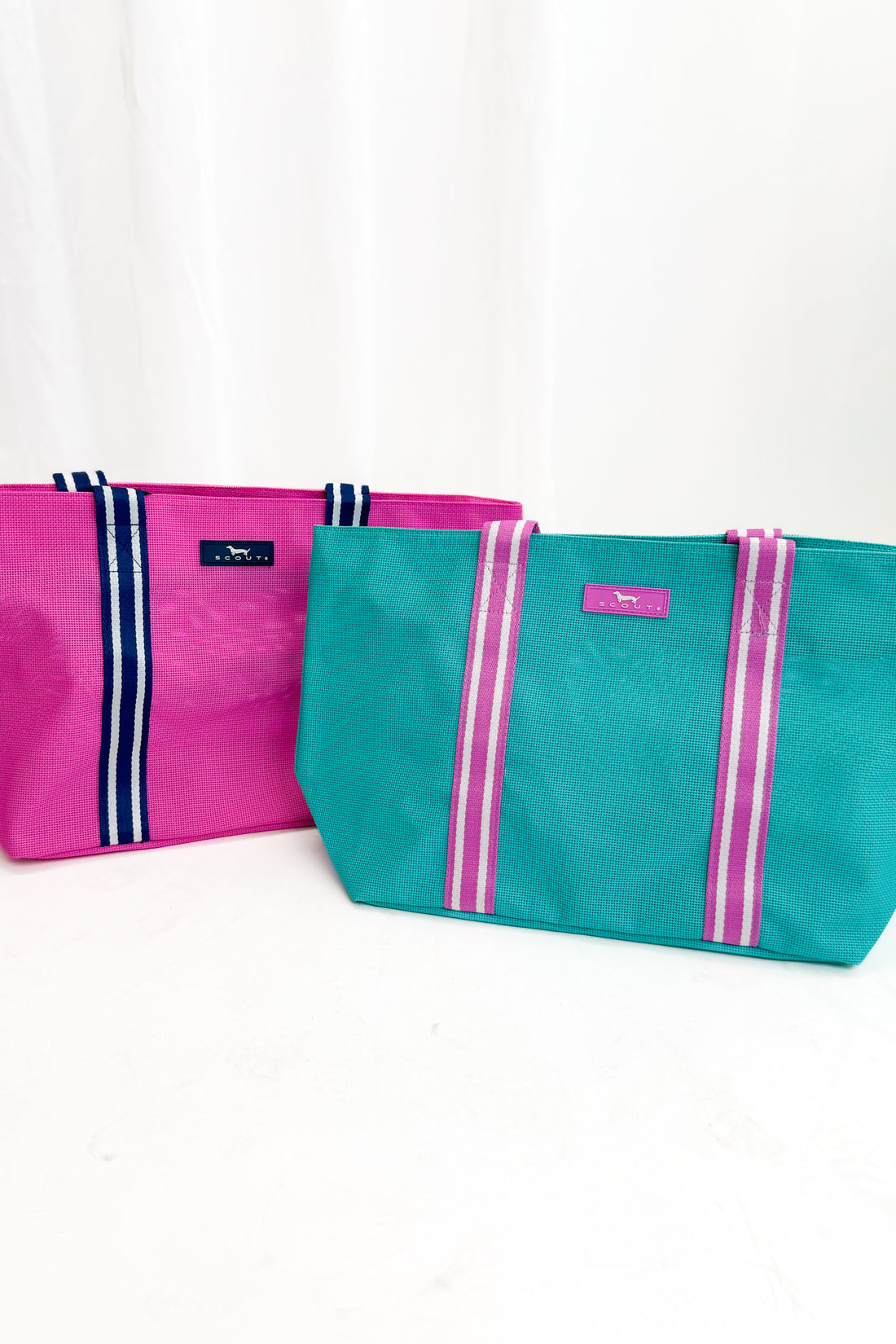 Two bags, one pink and one teal, with visible branding on a white background
