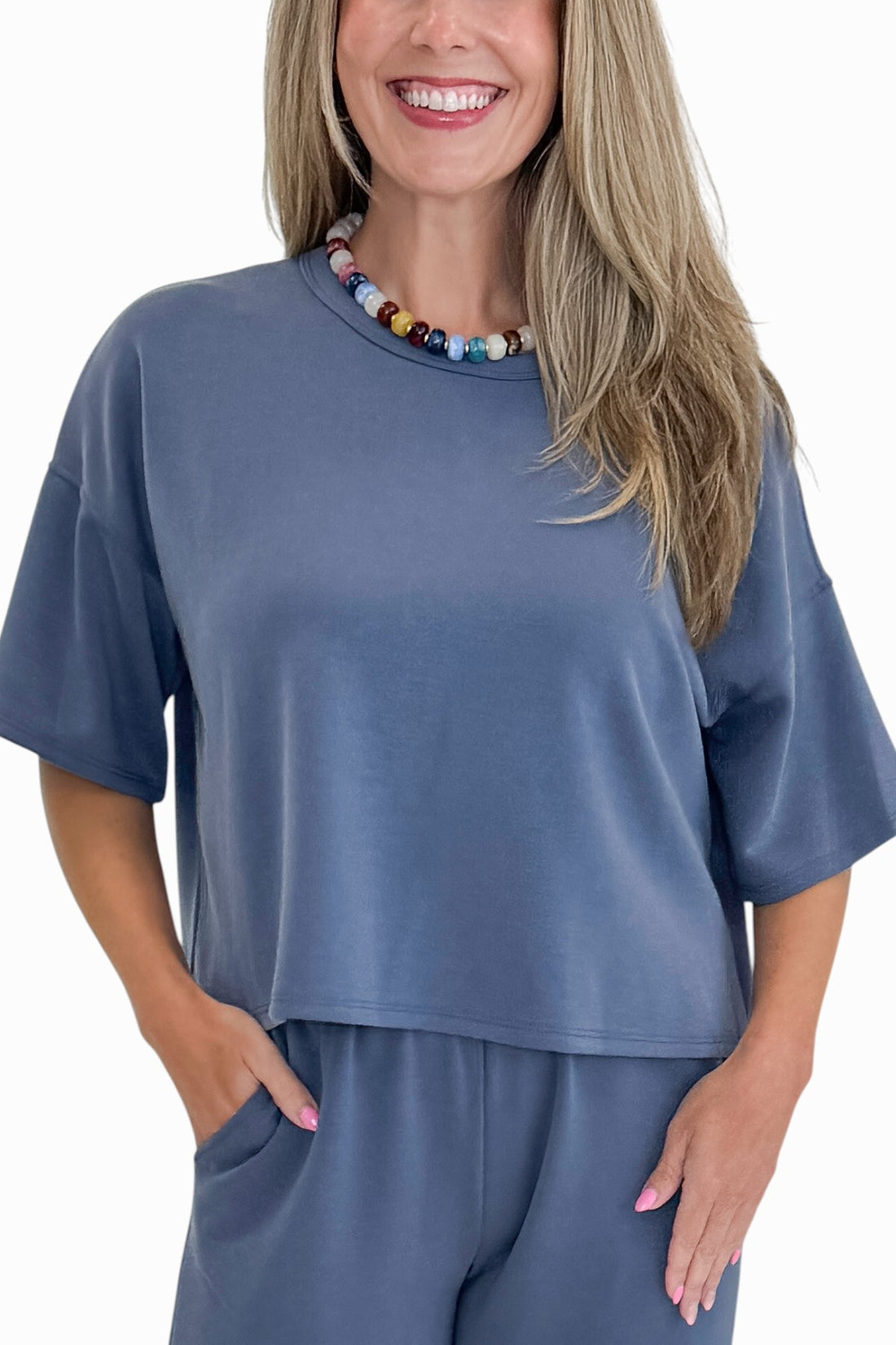 Front view of woman wearing Swagger Boutique’s Blue Cropped Lounge Pants and matching Blue Round Neck Short Sleeve Top against white studio background.