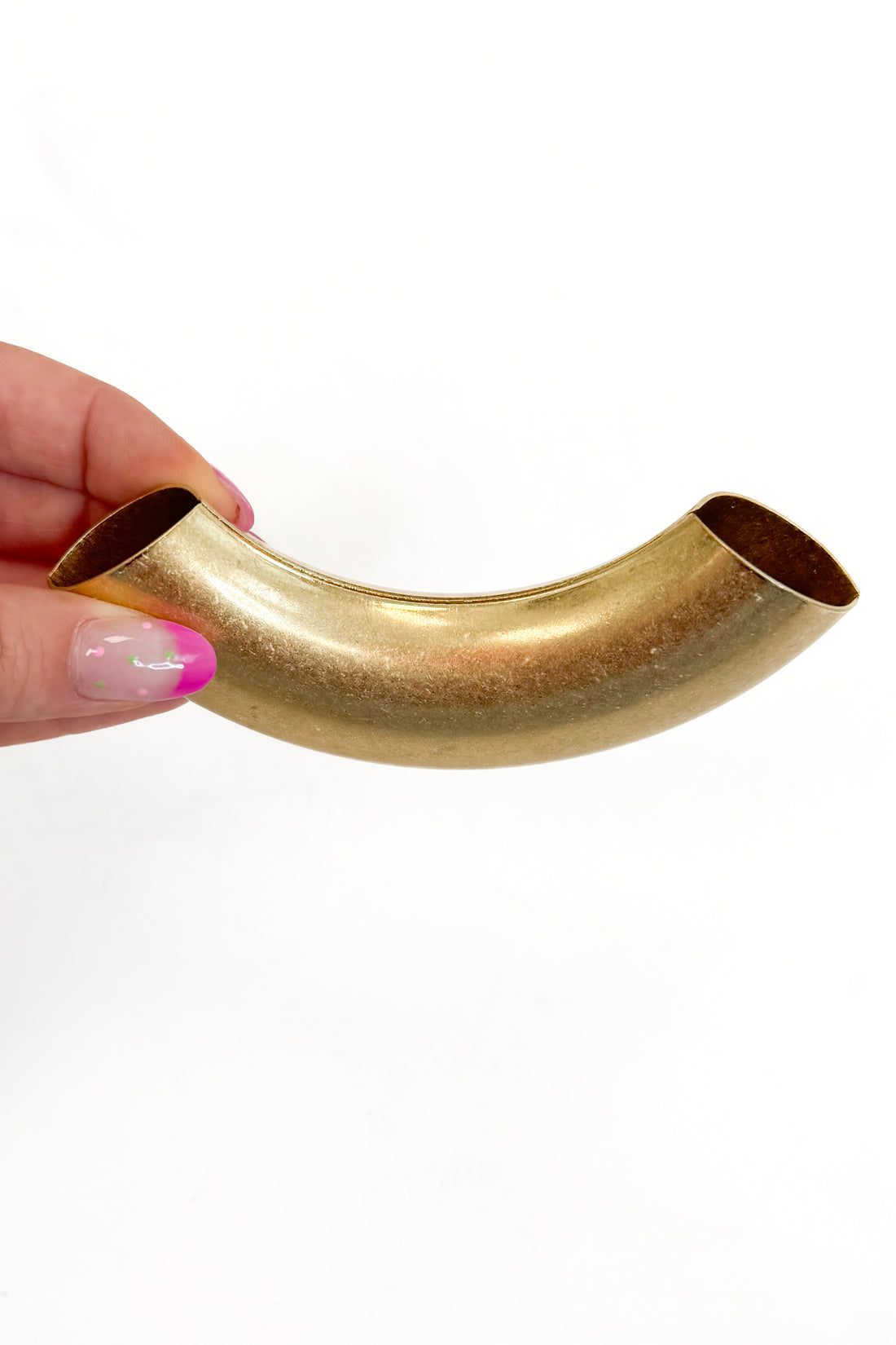 Hand holding a gold curved metal tube against a white background