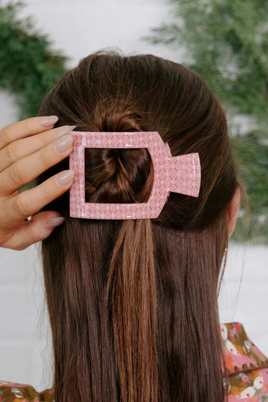 Person with a pink hair clip in their hair, with a blurred snowy background