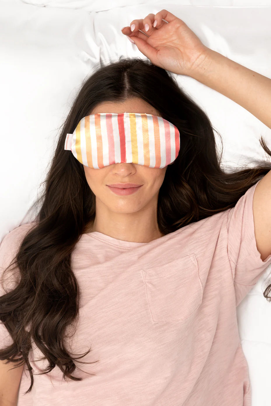 Woman wearing a colorful striped eye mask on a white background