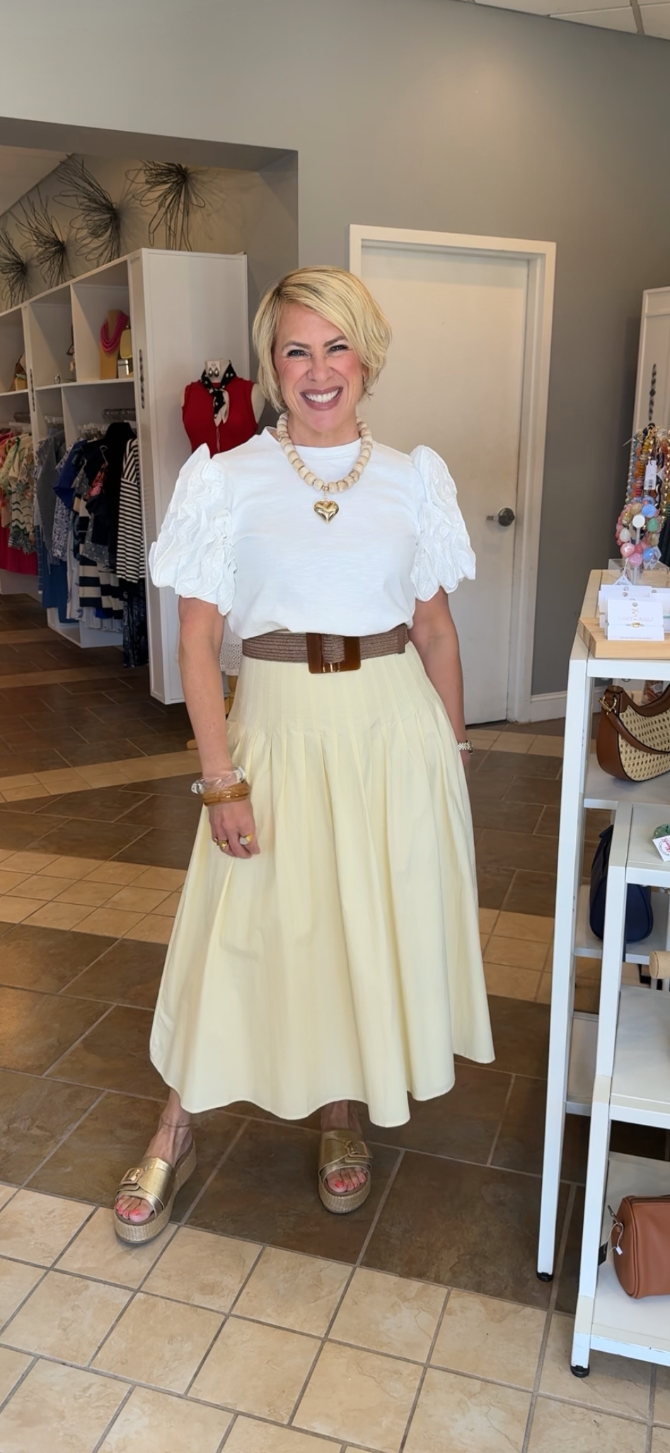 Woman in a white blouse and cream skirt standing in a store.
