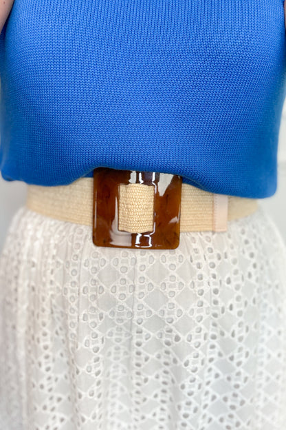 Blue top and white skirt with a beige belt featuring a large brown buckle.