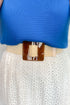 Blue top and white skirt with a beige belt featuring a large brown buckle.