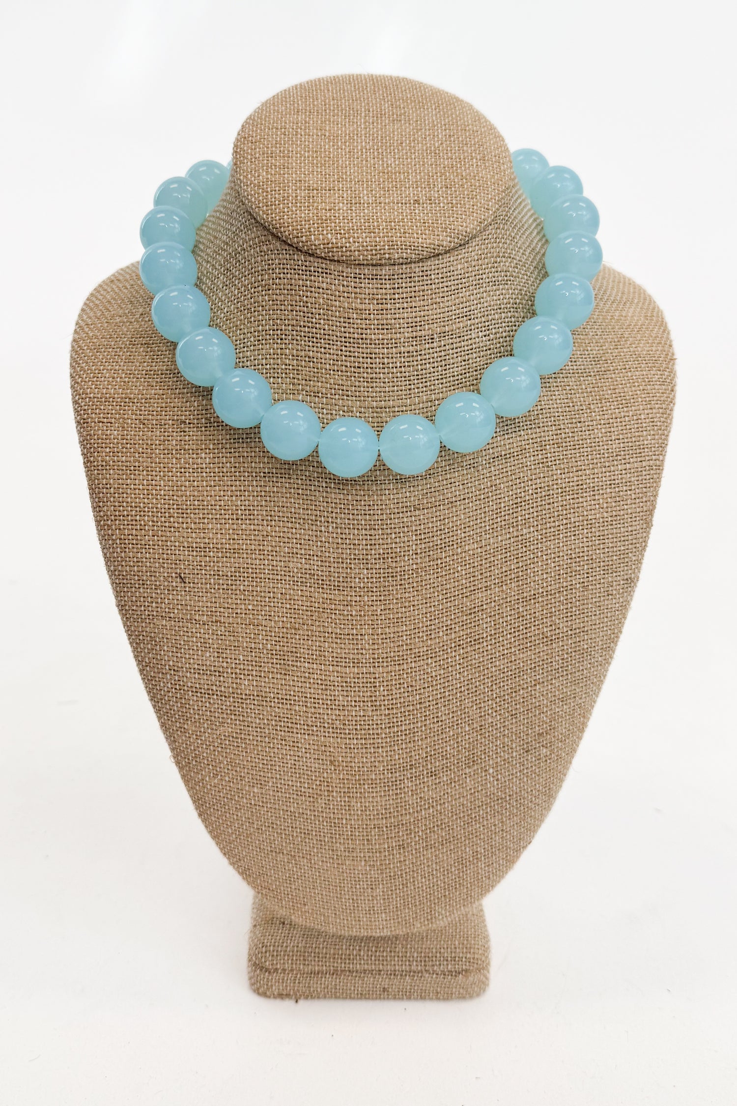 Light blue beaded necklace on a brown mannequin bust against a white background