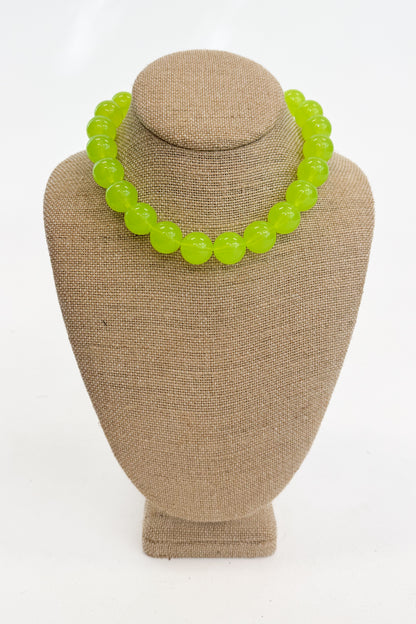 Neon green beaded necklace on a beige mannequin bust against a white background