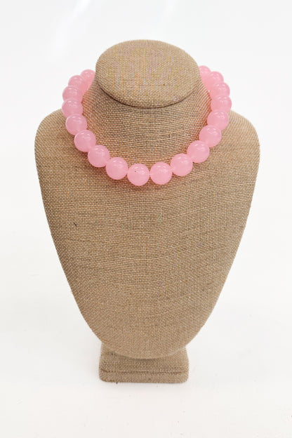Pink beaded necklace on a beige mannequin bust against a white background