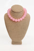 Pink beaded necklace on a beige mannequin bust against a white background