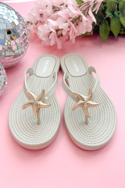 Nina- Ivory Shell Flip Flops against pink background