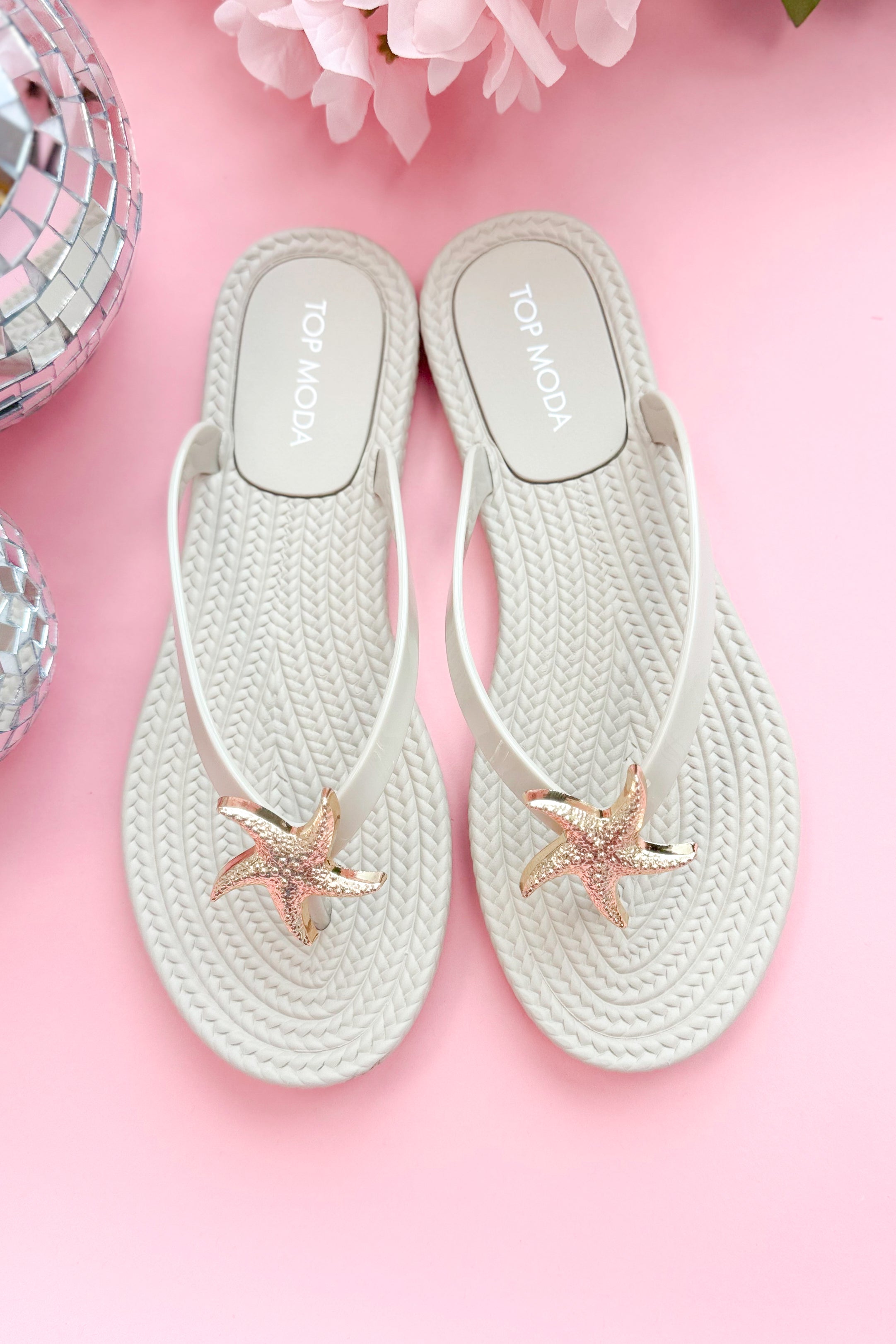 Nina- Ivory Shell Flip Flops against pink background