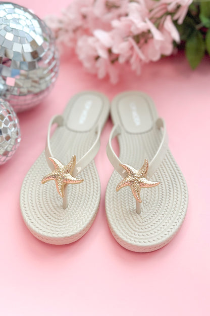 Nina- Ivory Shell Flip Flops against pink background