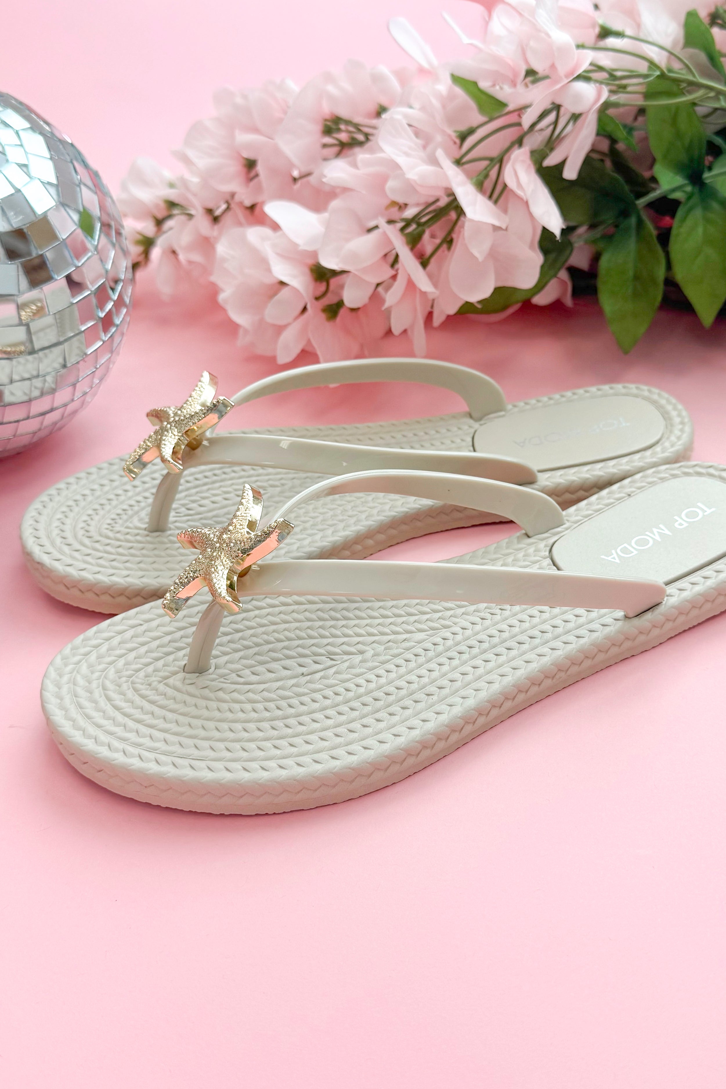 Nina- Ivory Shell Flip Flops against pink background side view