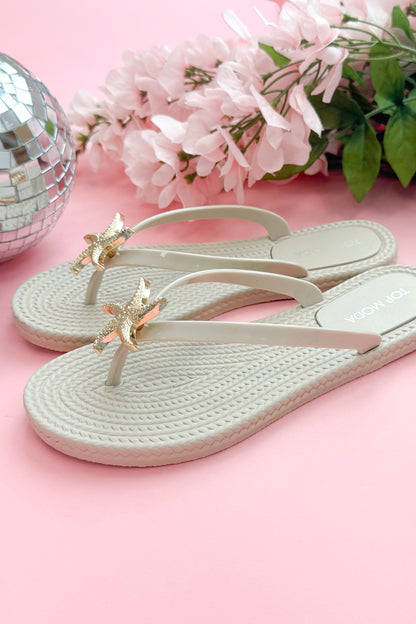 Nina- Ivory Shell Flip Flops against pink background side view