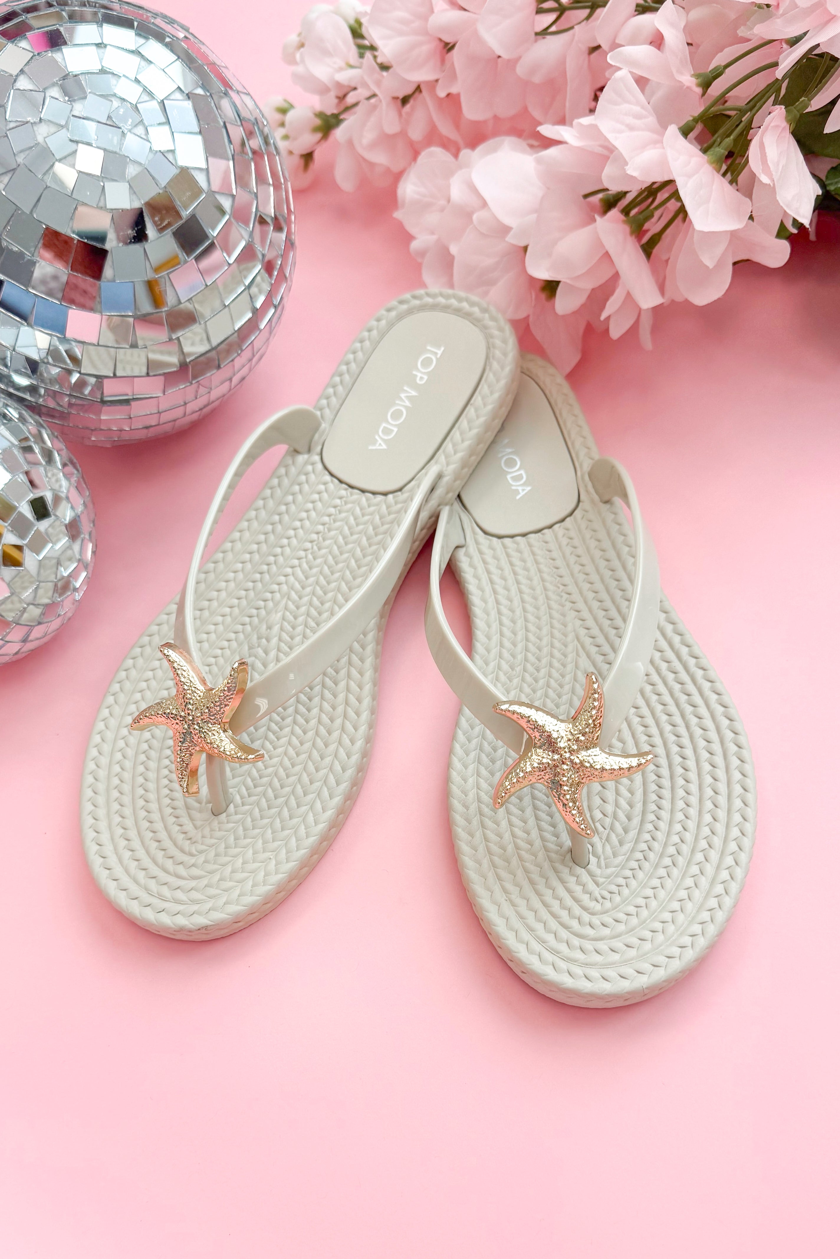 Nina- Ivory Shell Flip Flops against pink background