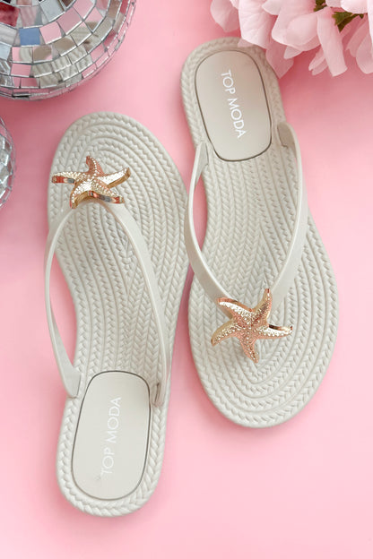Nina- Ivory Shell Flip Flops against pink background