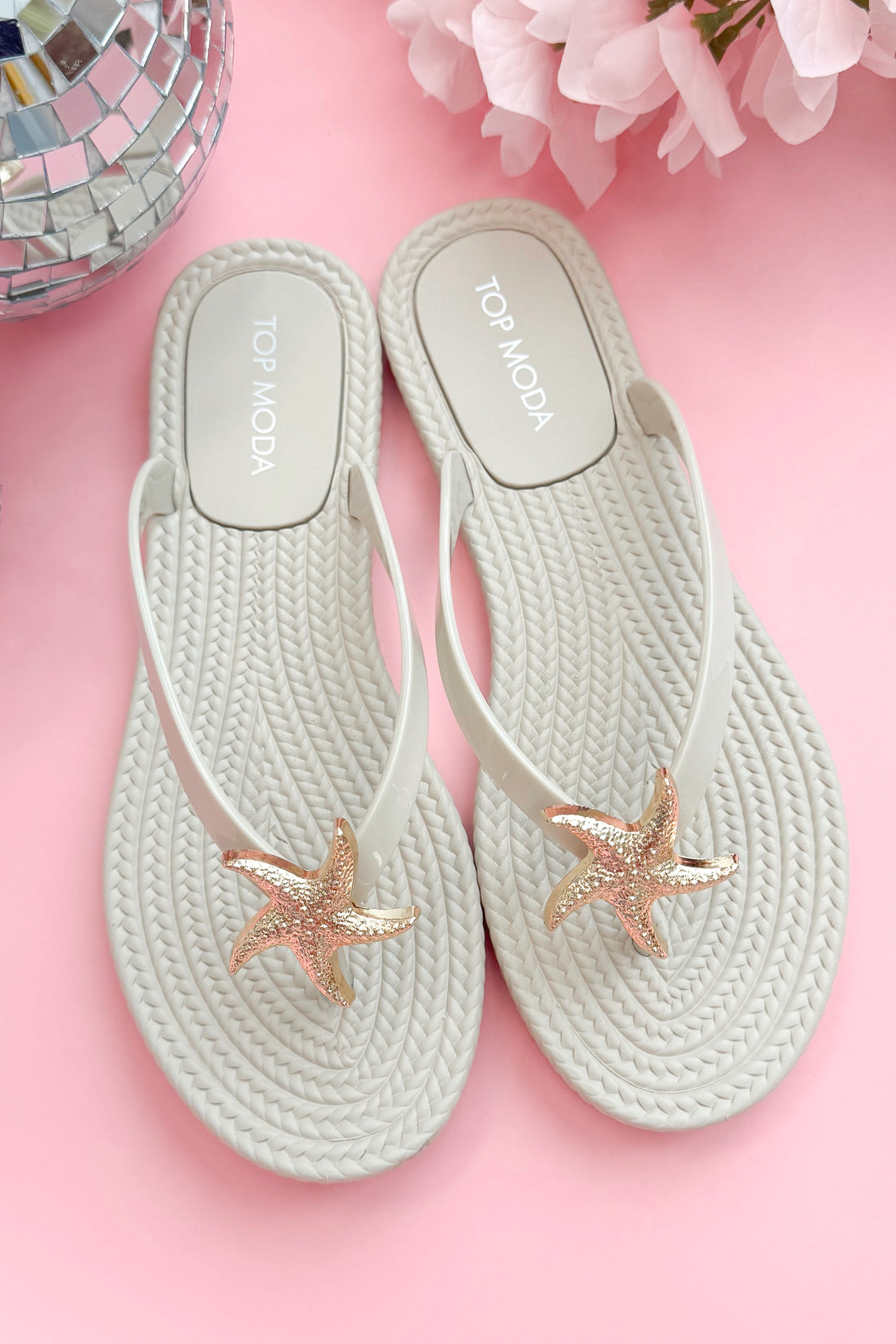 Nina- Ivory Shell Flip Flops against pink background