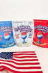 Three colorful packaging designs for drink mixes with a red, white, and blue theme, featuring an American flag in the foreground.