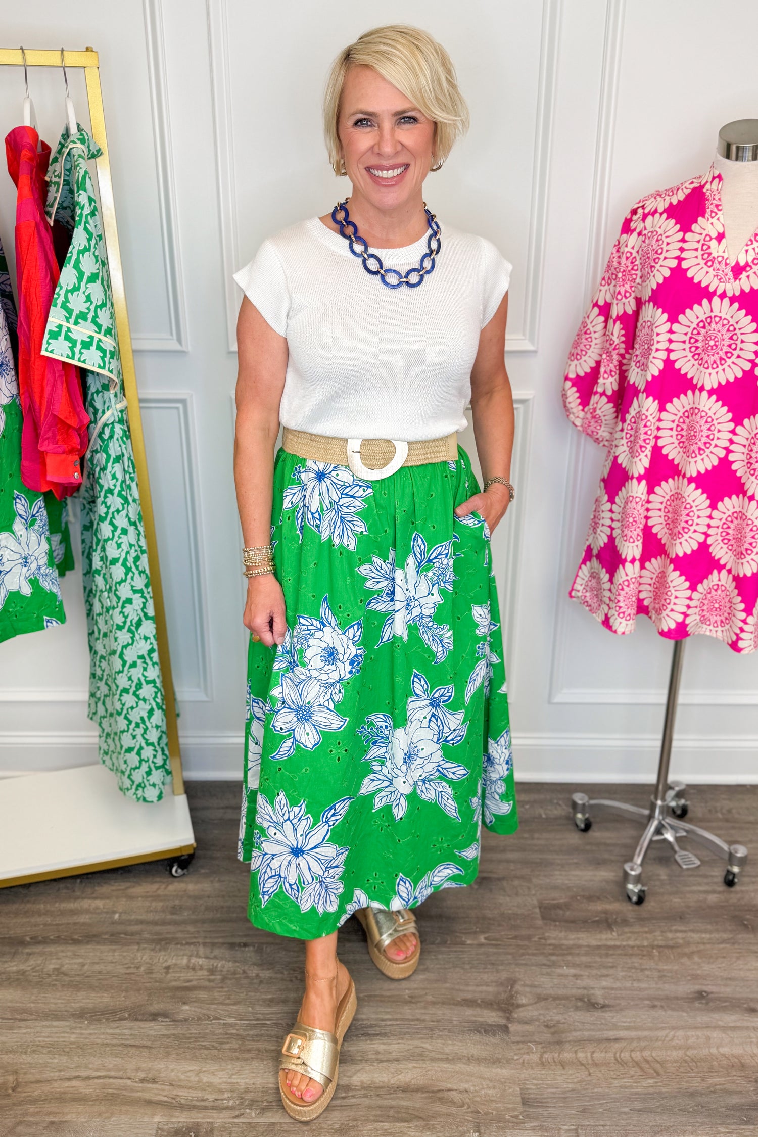 woman wearing green eyelet detailing skirt with white and blue printed flowers paired with a white top and blue necklace