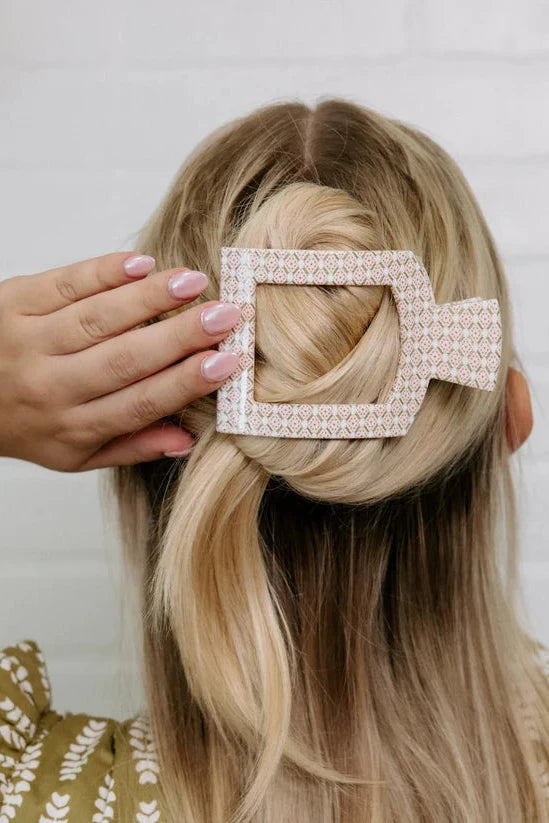 Person with a decorative hair clip in their hair against a neutral background