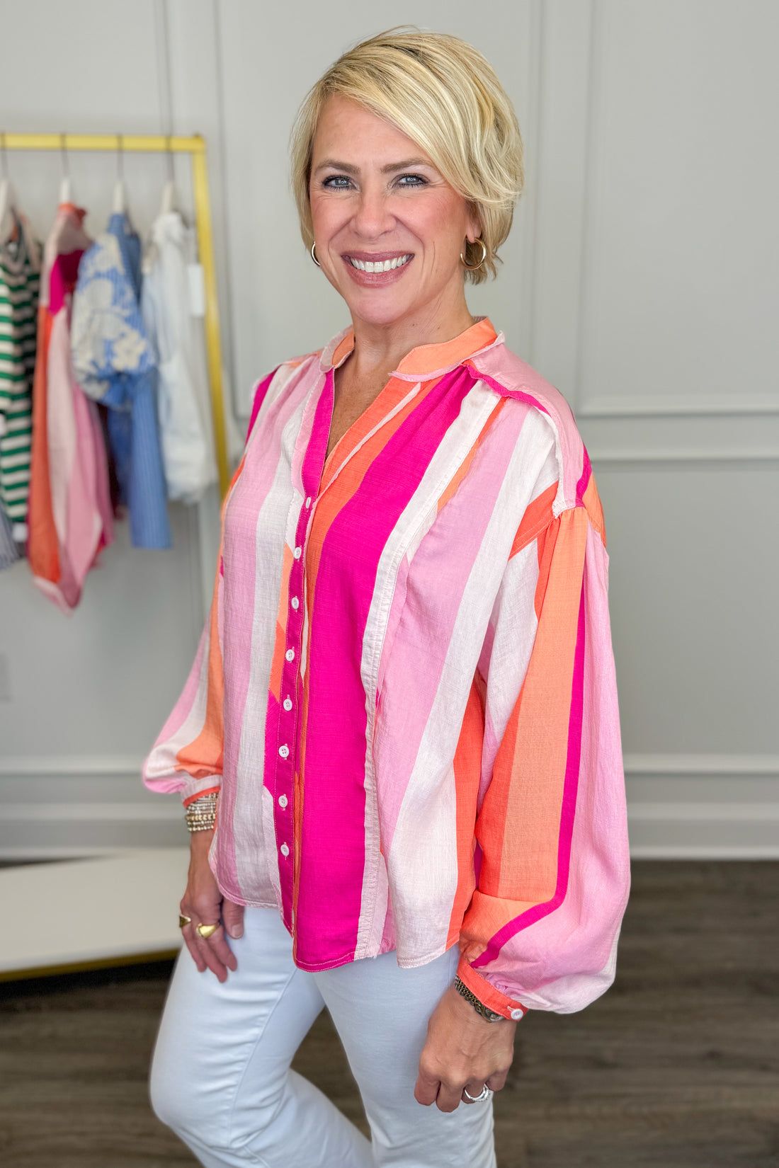 Woman wearing a colorful striped shirt in a clothing store.