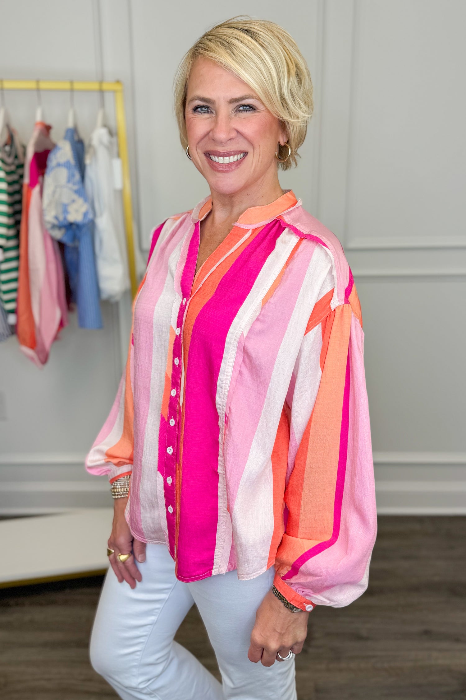Woman wearing a colorful striped shirt in a clothing store.