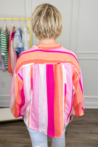 Person wearing a colorful striped shirt in a clothing store.