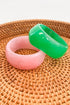 Pink and green bangles on a woven surface