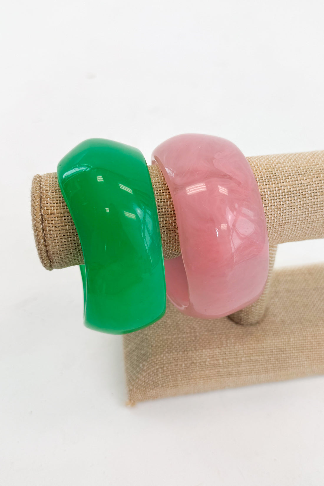 Two colorful bangles, one green and one pink, on a white background.