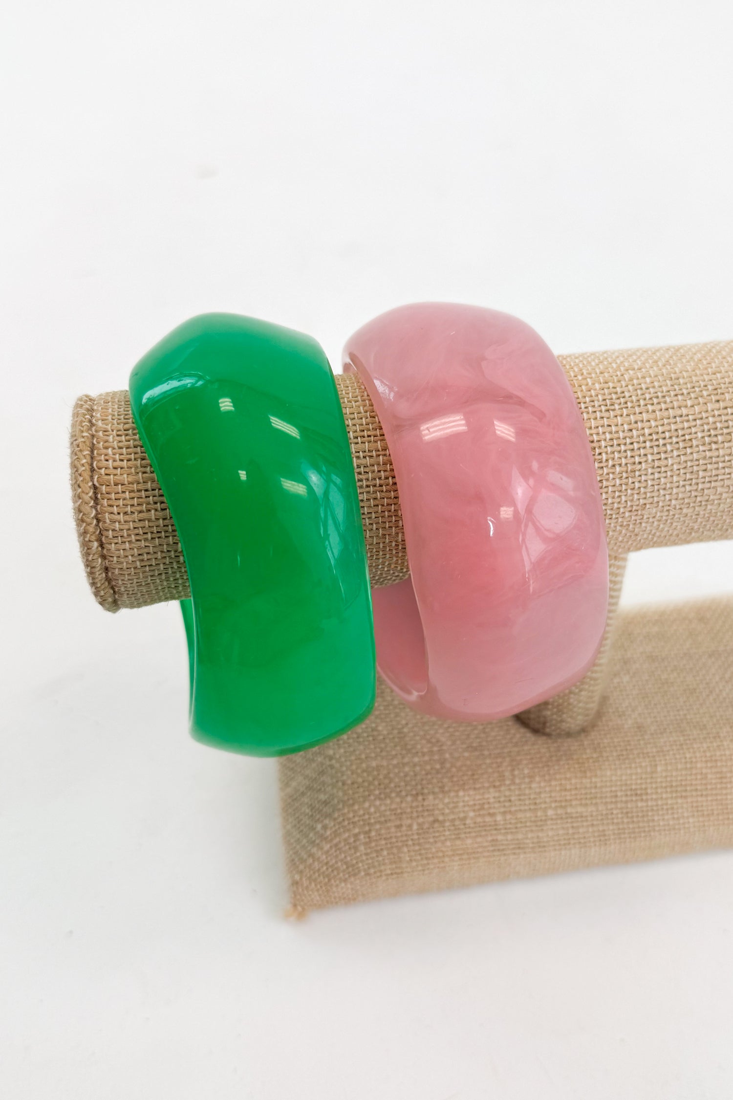 Two colorful bangles, one green and one pink, on a white background.