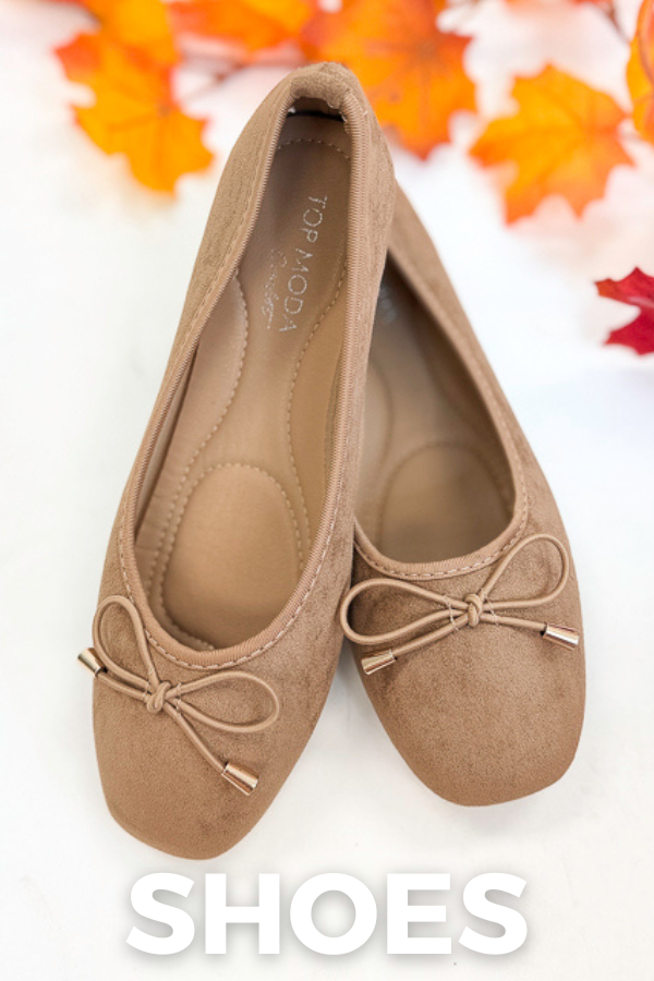 A pair of beige suede ballet flats with small bow details on the toes, displayed on a white surface with autumn leaves in the background and a 'SHOES' text overlay at the bottom.