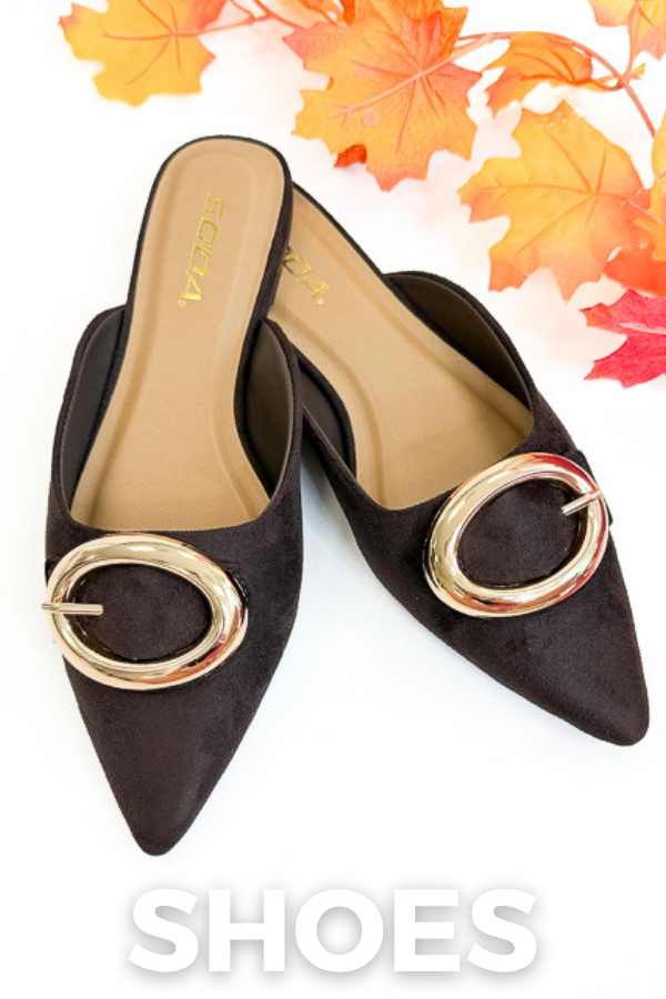 A pair of pointed-toe slip-on mule shoes in dark brown suede with large gold-tone oval ring hardware on the front, shown on a white background with autumn leaves at the top and a large 'SHOES' text overlay at the bottom.
