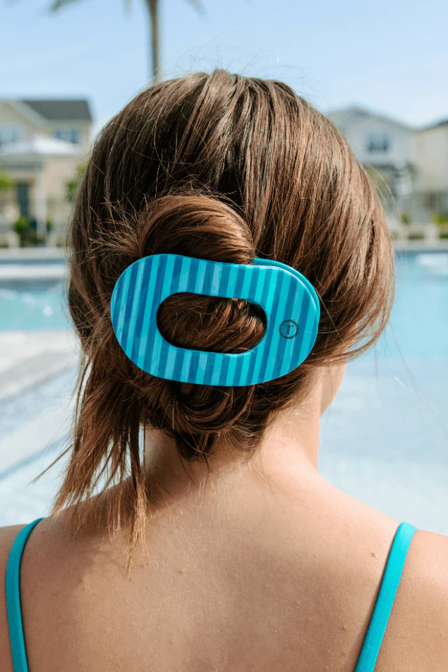 Person with a blue striped hair tie in their bun by a pool