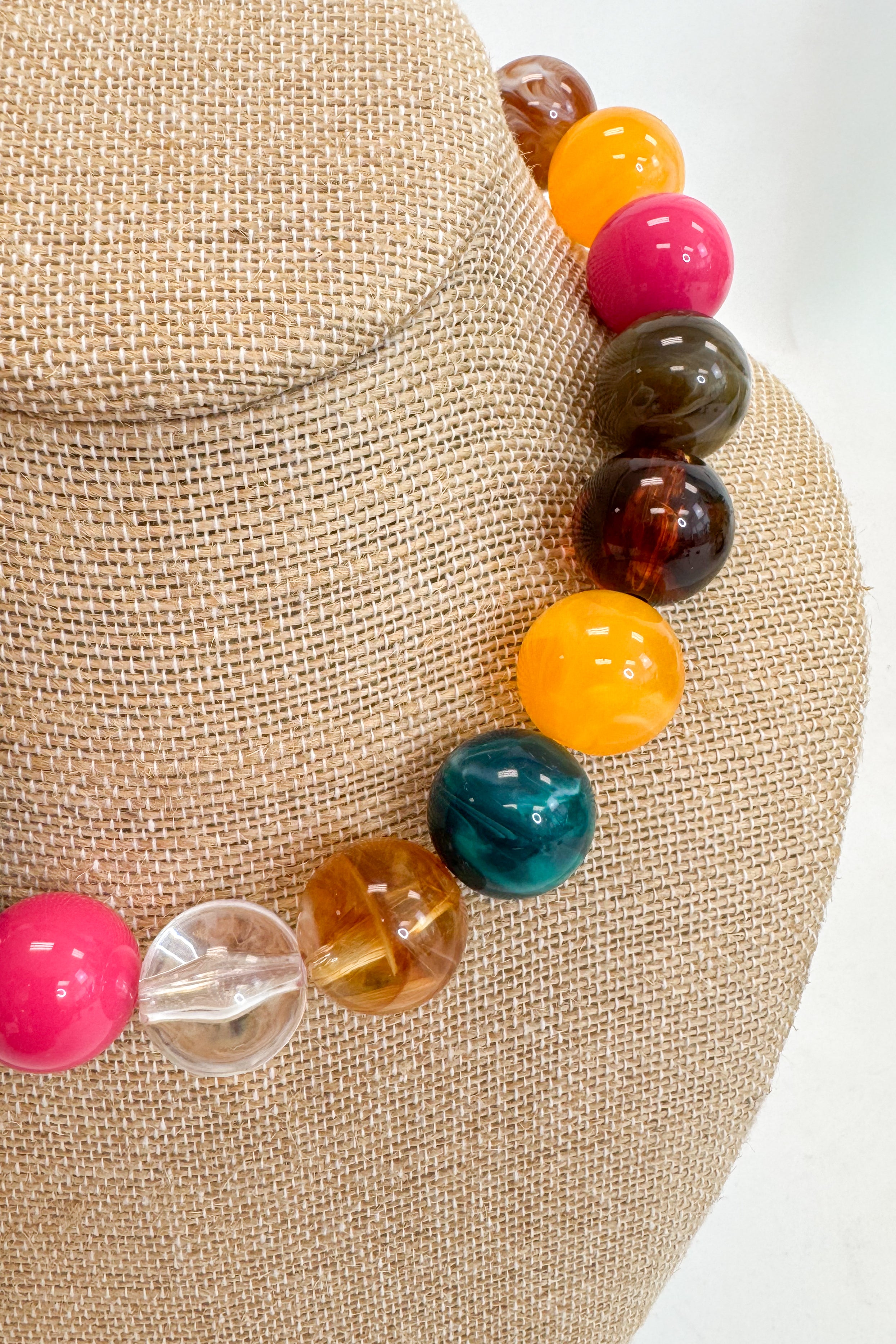 Colorful beaded bracelet on a mannequin head with a neutral background