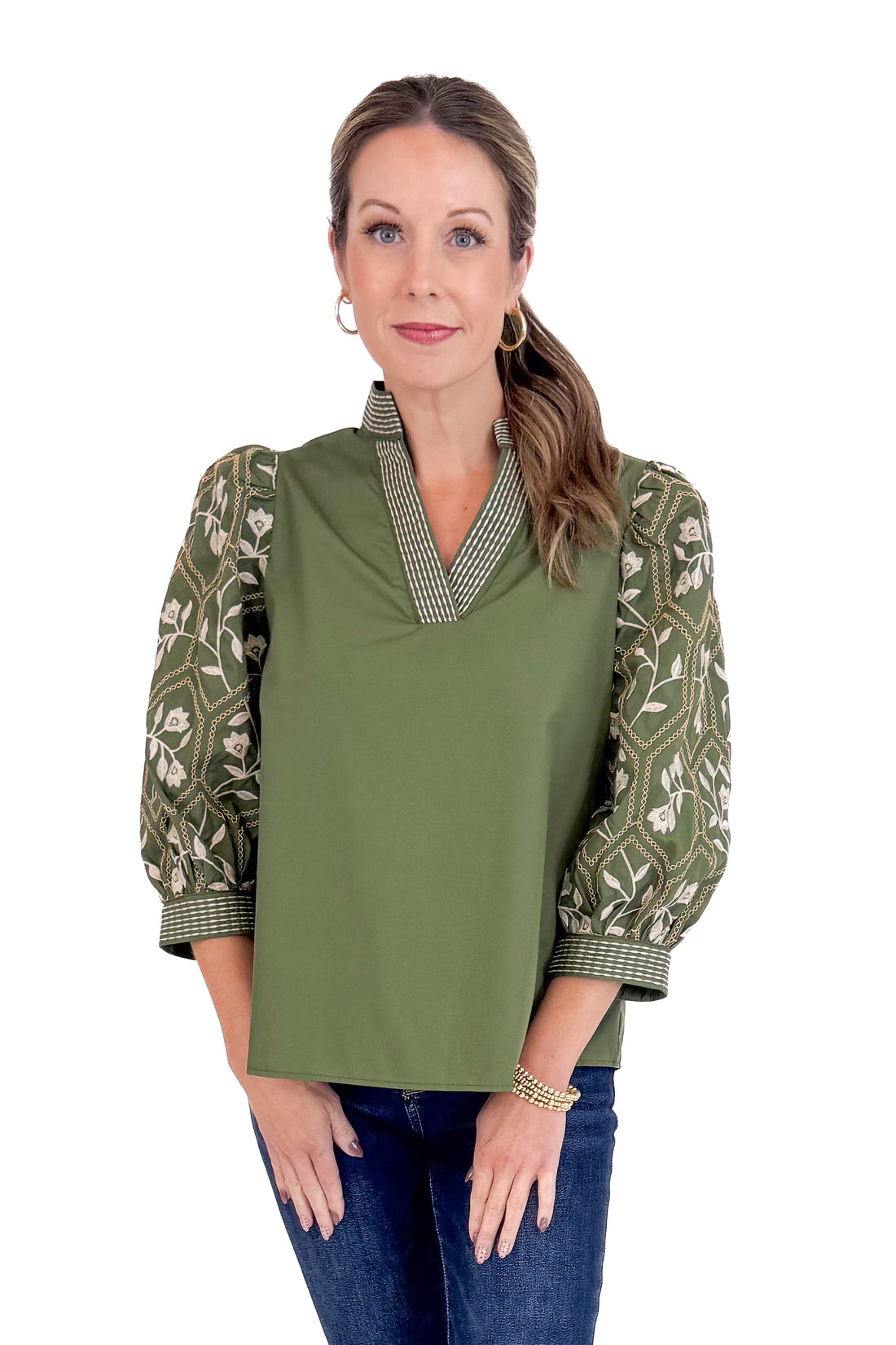 Woman wearing a green blouse with patterned sleeves on a white background