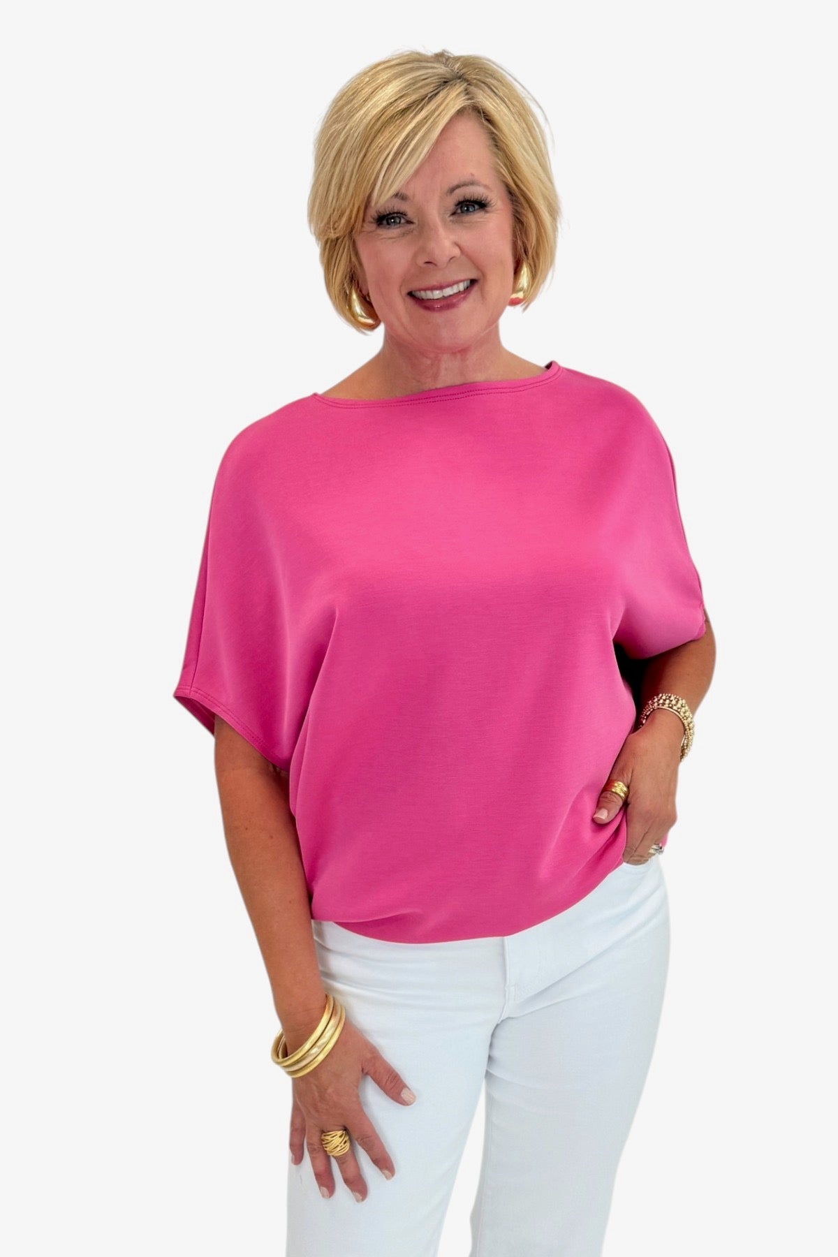 Woman wearing a bright pink top and white pants on a white background