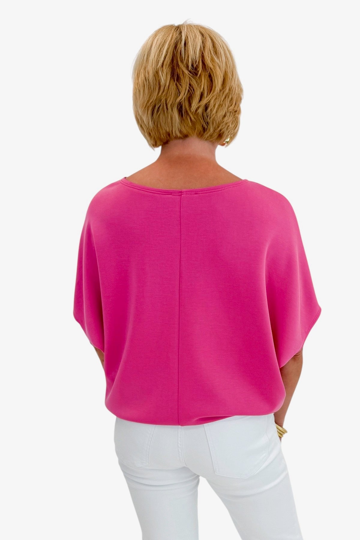 Person wearing a bright pink top and white pants on a white background