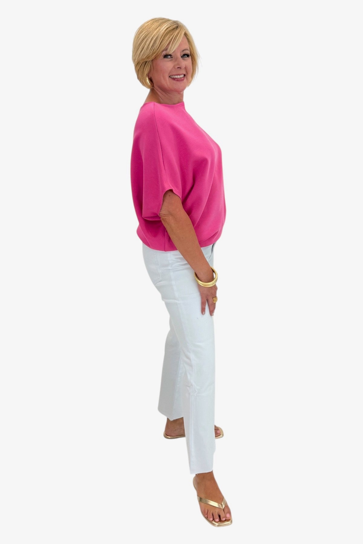 Woman wearing a pink top and white pants on a white background