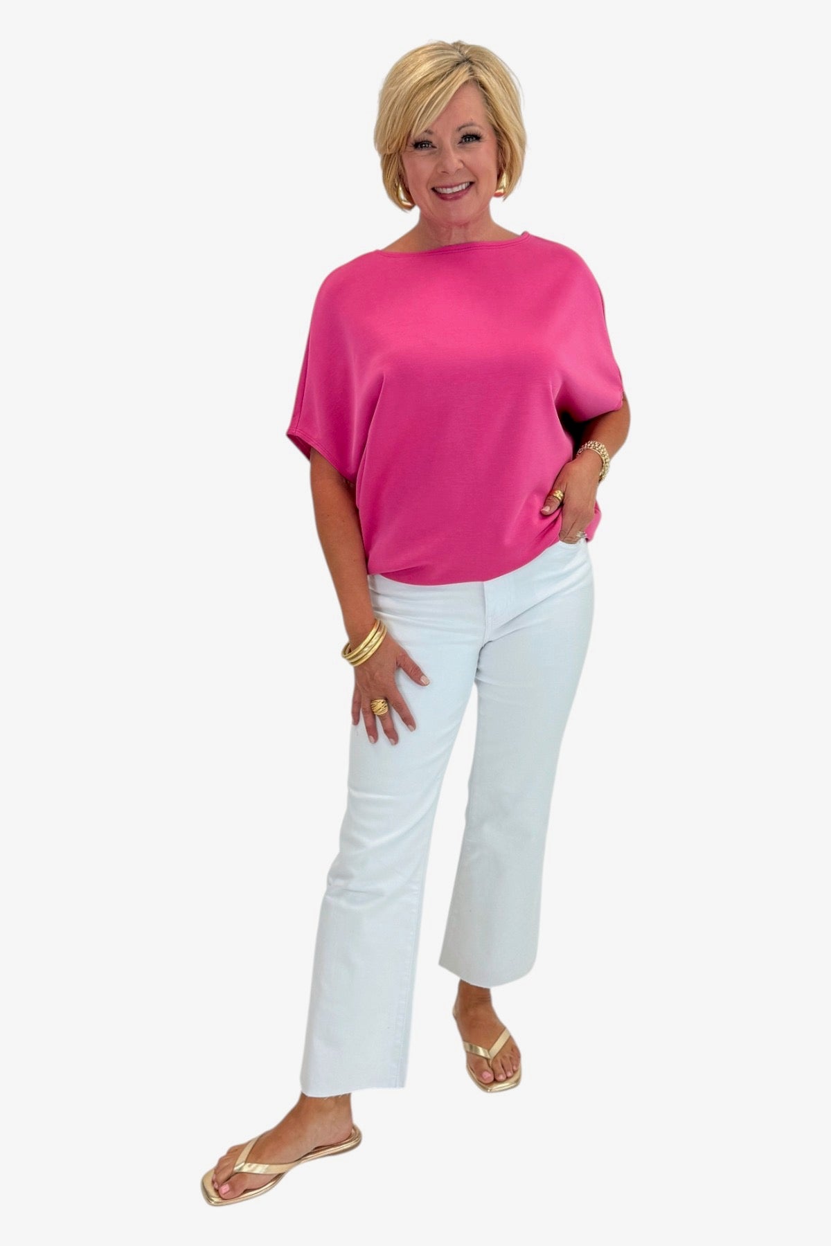 Woman wearing a pink top and white pants on a white background