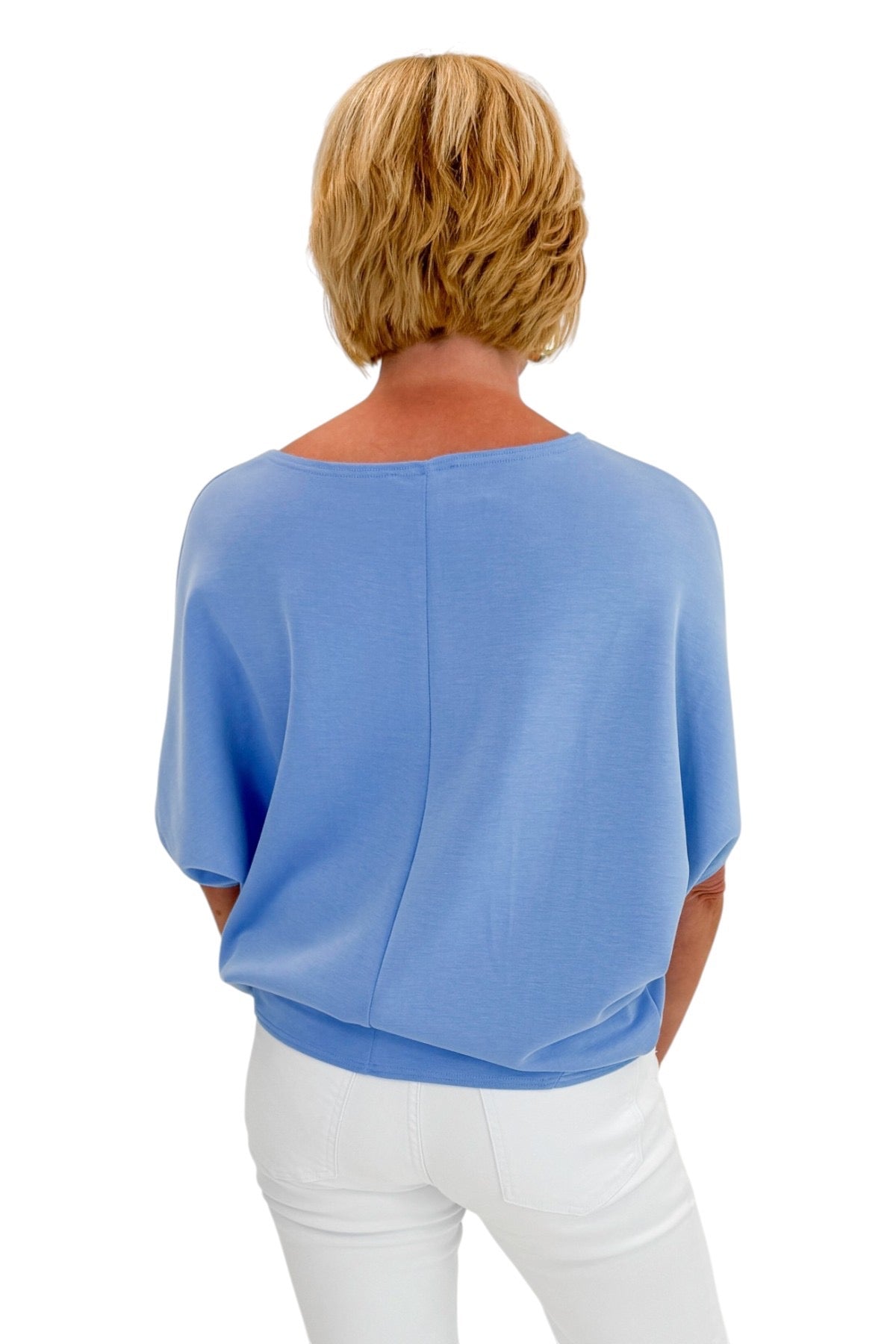 Person wearing a blue top and white pants on a white background