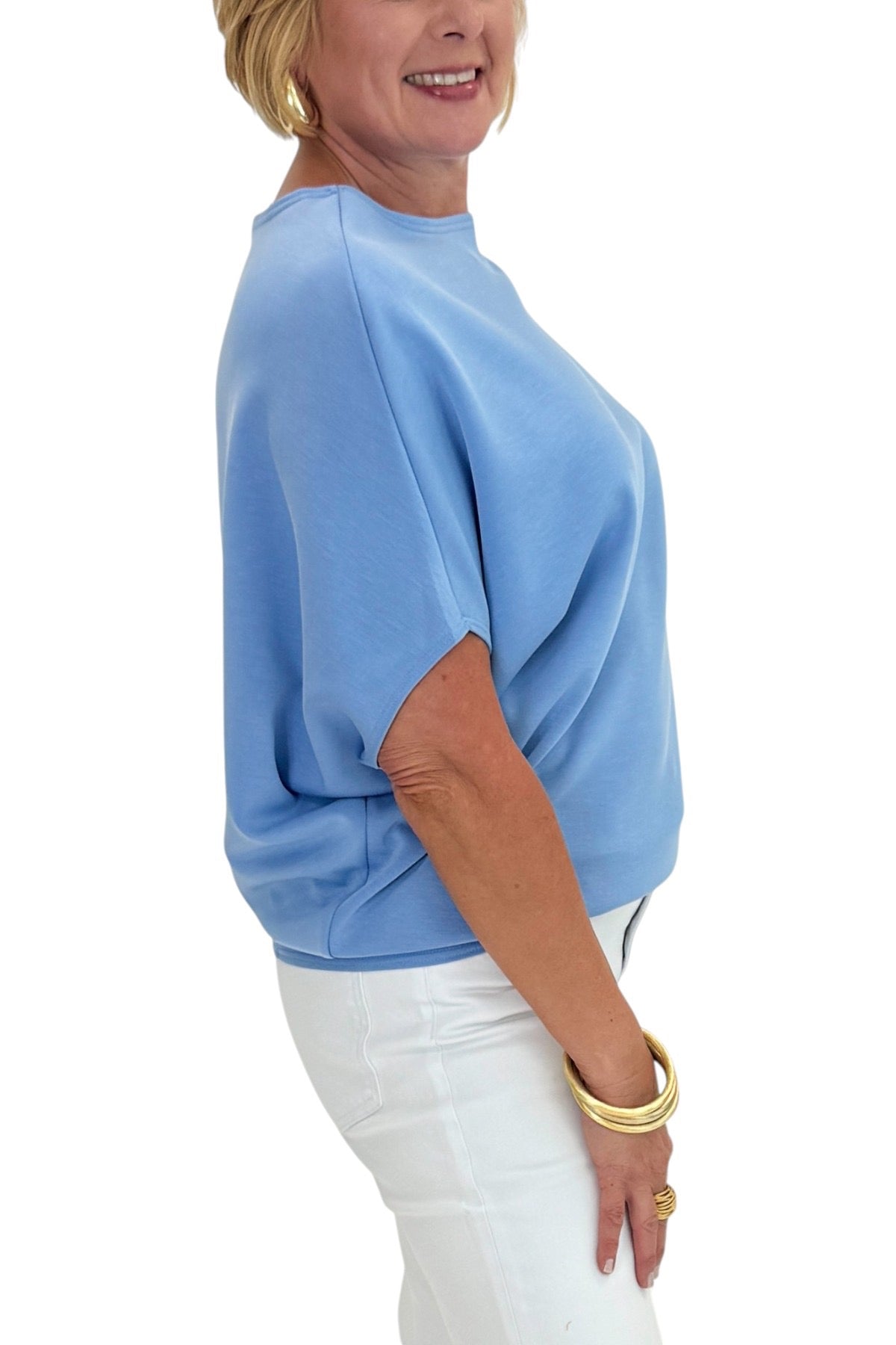 Woman wearing a blue top and white pants on a white background