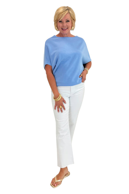 Woman wearing a light blue top and white pants on a white background