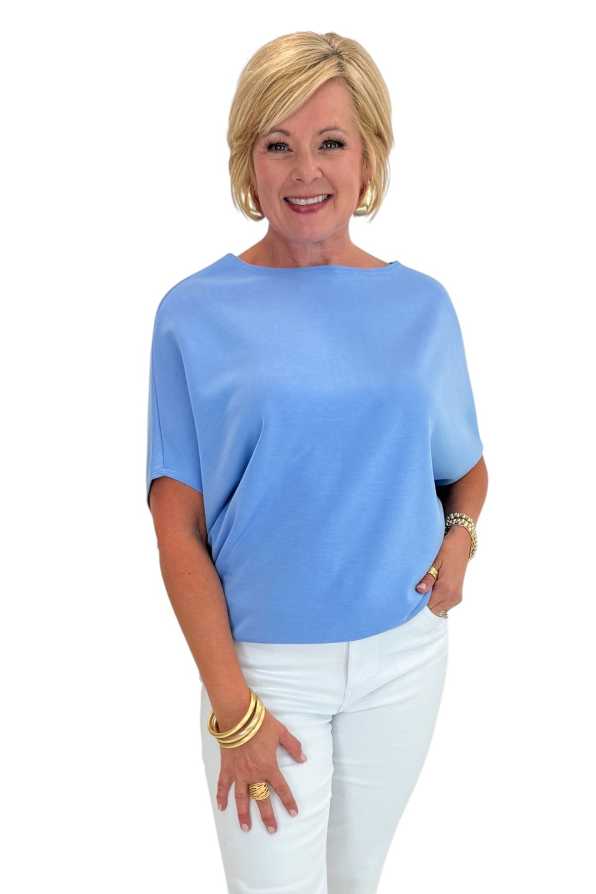 Woman wearing a blue top and white pants on a white background