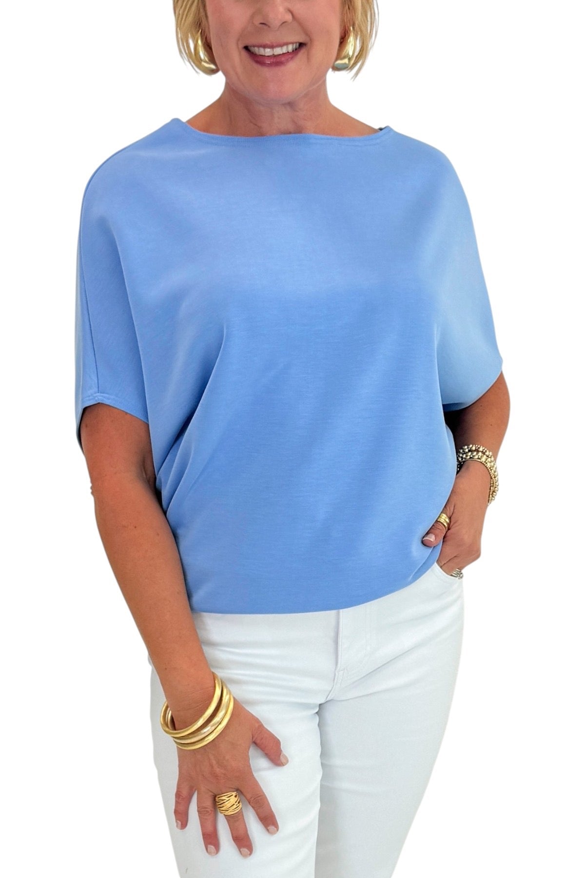 Woman wearing a blue top and white pants on a white background