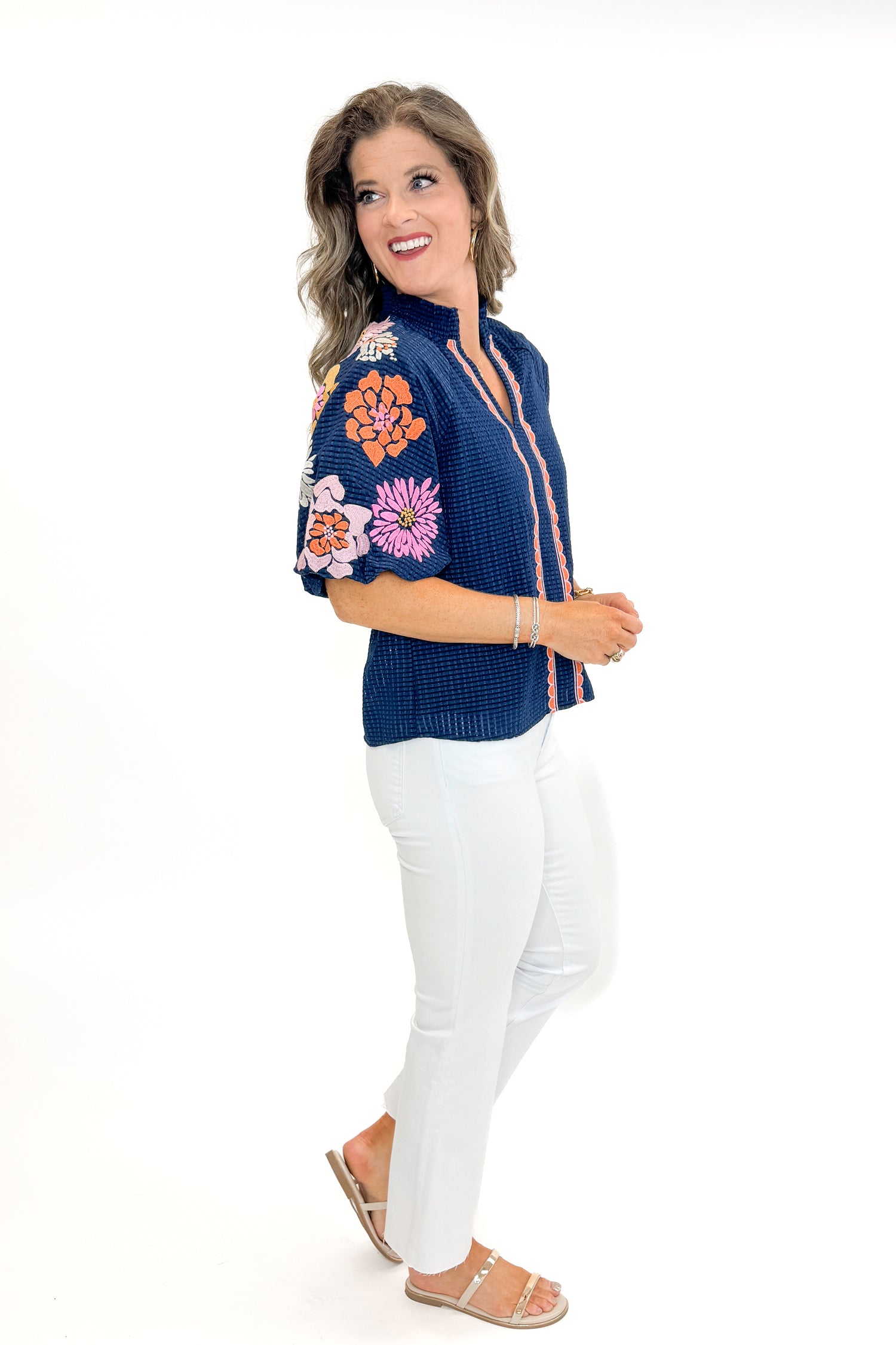Side view of woman wearing Navy Textured &amp; Floral Embroidered Top by THML with jeans against white studio background.