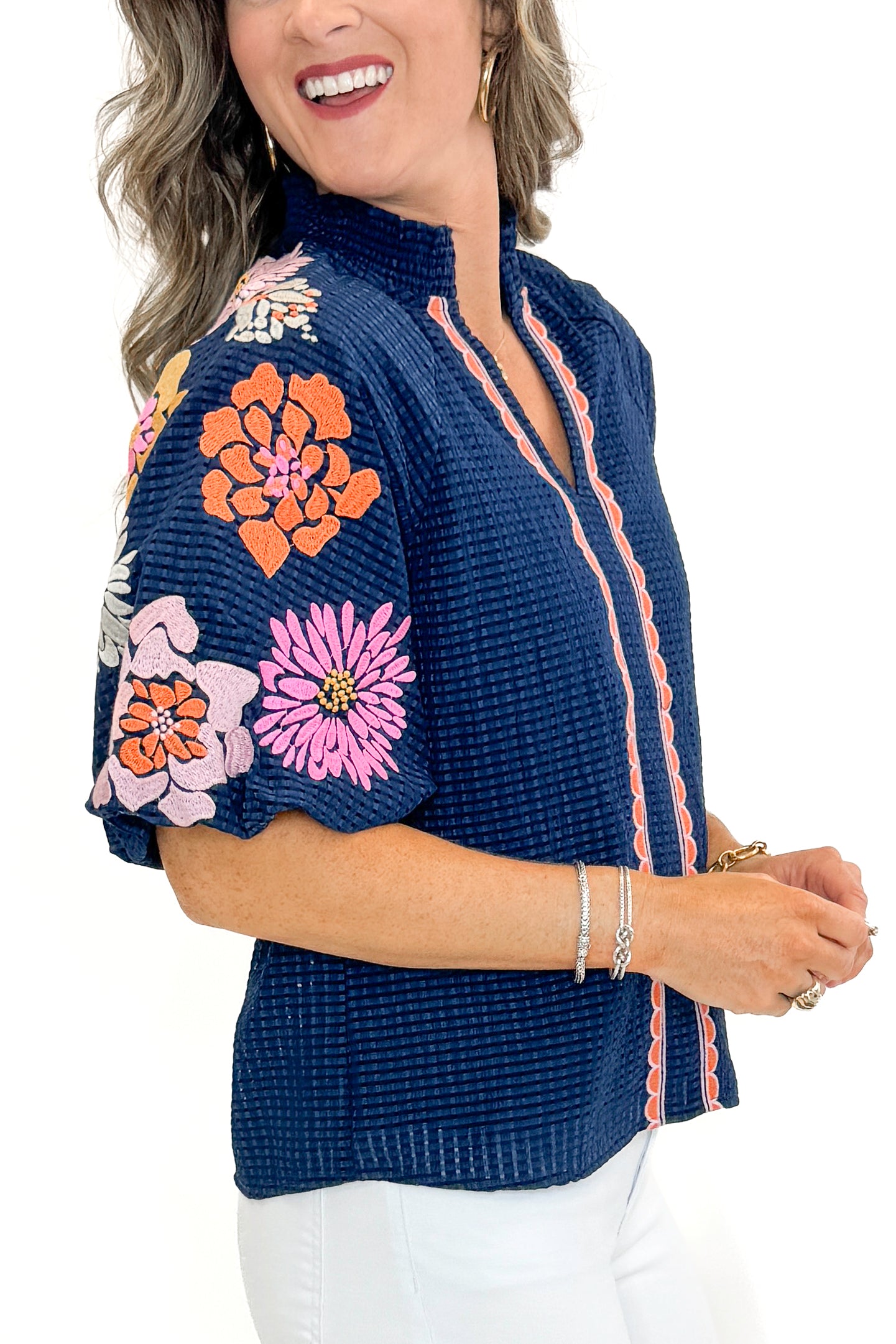 Side view of woman wearing Navy Textured &amp; Floral Embroidered Top by THML with jeans against white studio background.