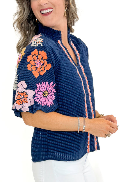 Side view of woman wearing Navy Textured &amp; Floral Embroidered Top by THML with jeans against white studio background.