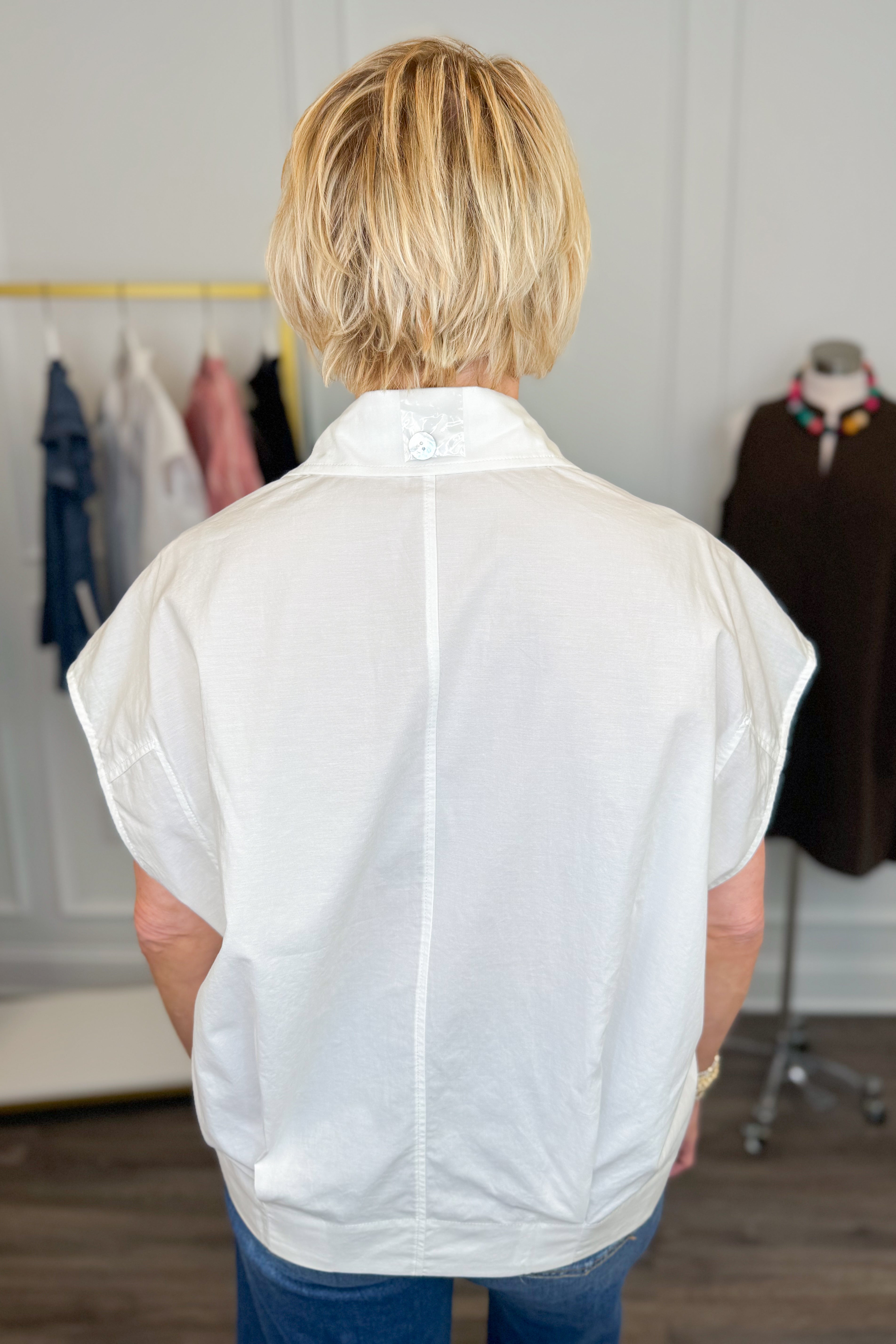 Person wearing a white sleeveless shirt in a clothing store setting